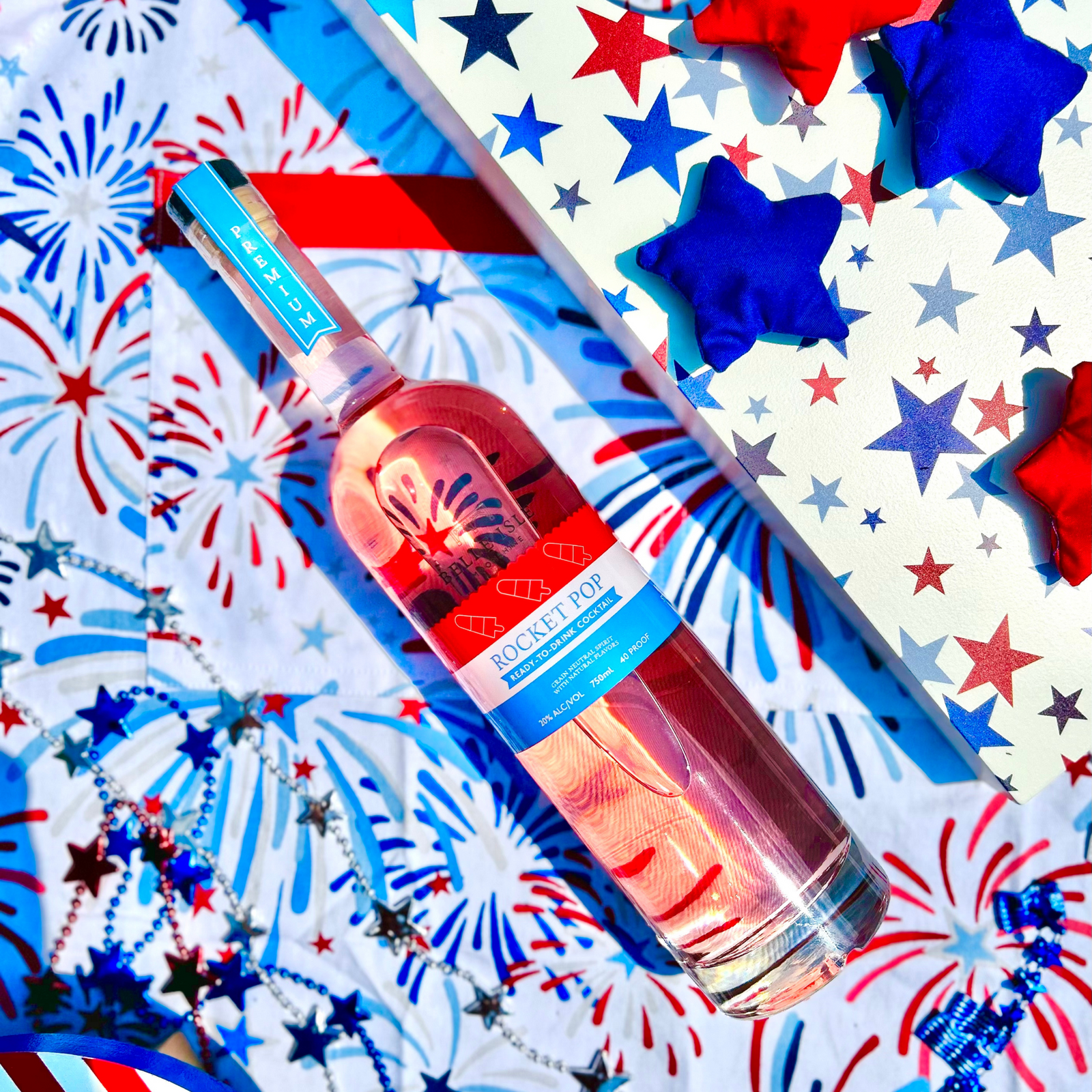 A bottle of Belle Isle Rocket Pop cocktail infused with flavors of cherry, blue raspberry, and lemon, presented on a background with red, white, and blue colors and star patterns.