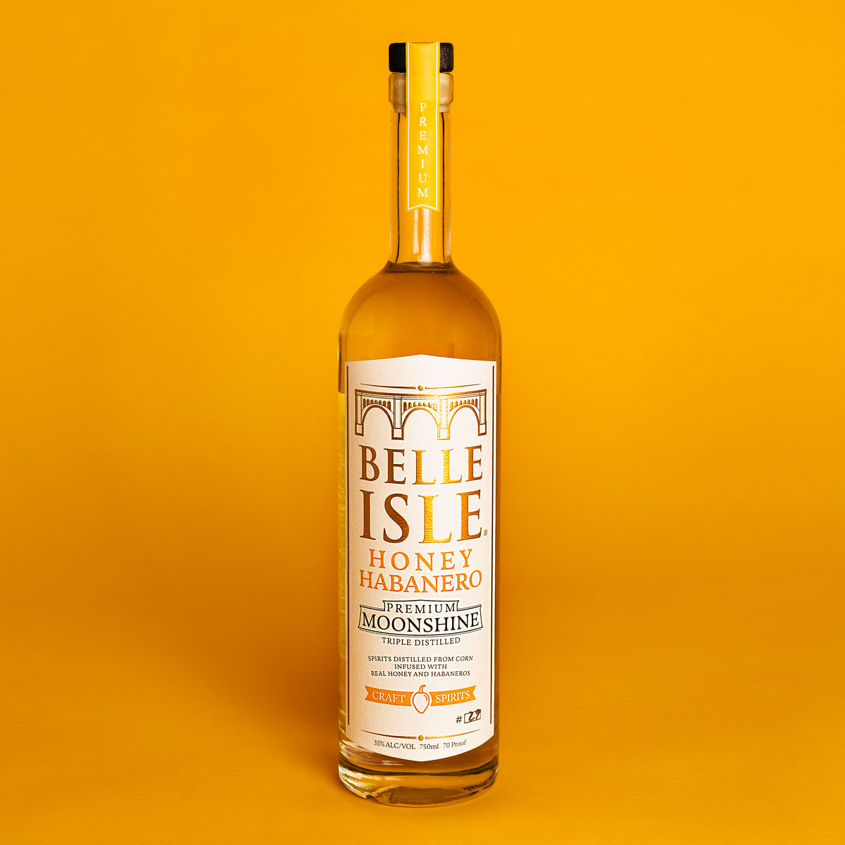 A bottle of Belle Isle Honey Habanero moonshine with a yellow label on a yellow background.